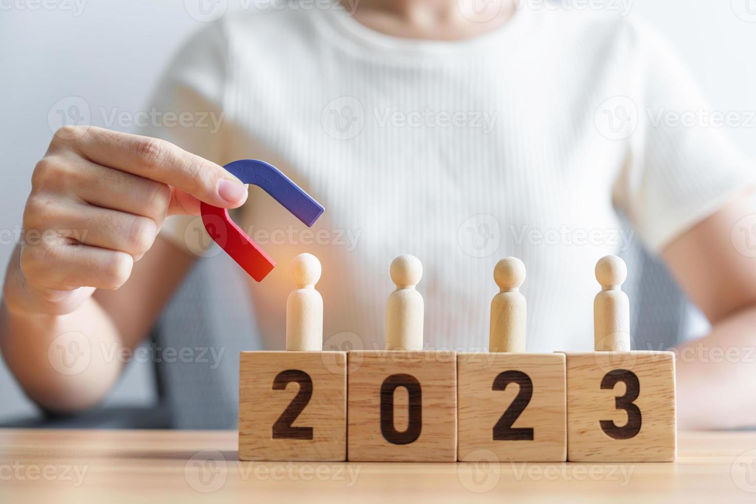 mano Tenere magnete e traino uomo di legno figura a partire dal il folla dipendente con 2023 anno bloccare. umano risorsa gestione, reclutamento, lavoro di squadra, strategia, tossico persone e comando concetti foto