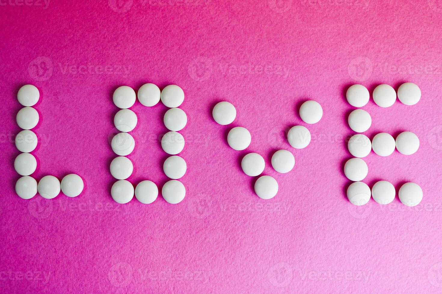 bellissimo iscrizione amore fatto a partire dal bianca il giro liscio medico pillole, vitamine, antibiotici e copia spazio su un' luminosa viola rosa sfondo. piatto posare foto