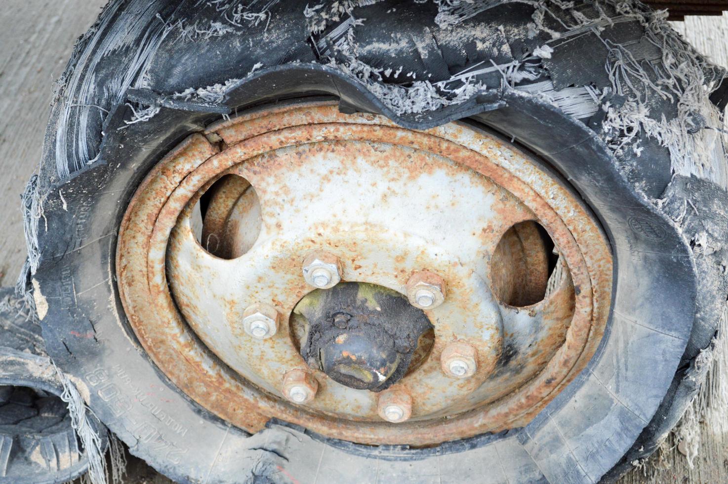 un' grande nero arrugginito gomma da cancellare ruota con un' strappato logoro su rotto cattivo vecchio pieno di pneumatici insicuro pneumatico foto