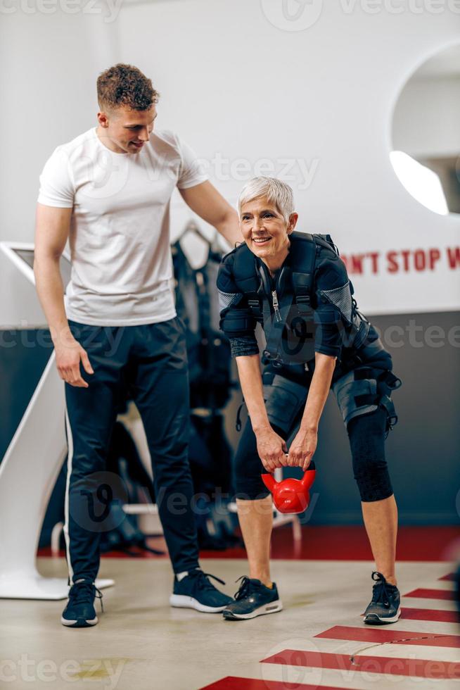 anziano donna fare ems allenarsi con allenatore nel il Palestra foto