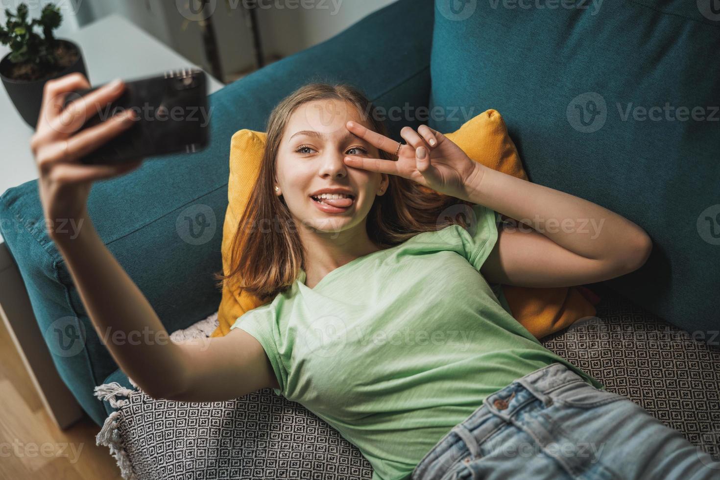 adolescente ragazza utilizzando inteligente Telefono mentre avendo tempo libero tempo a sua casa foto