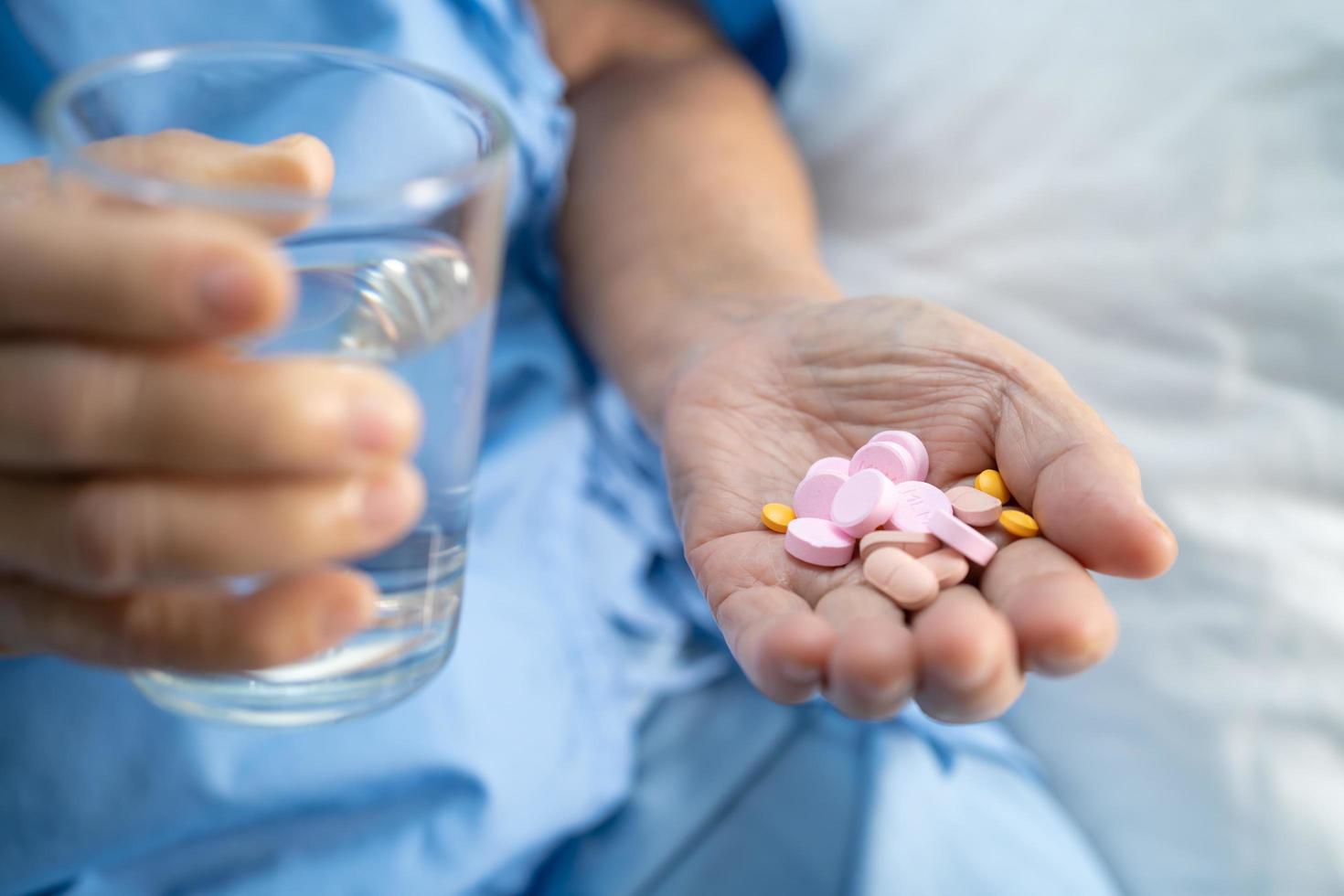 asiatico anziano anziano vecchio signora donna Tenere vitamina pillole droga nel sua mano, salutare forte medico concetto. foto