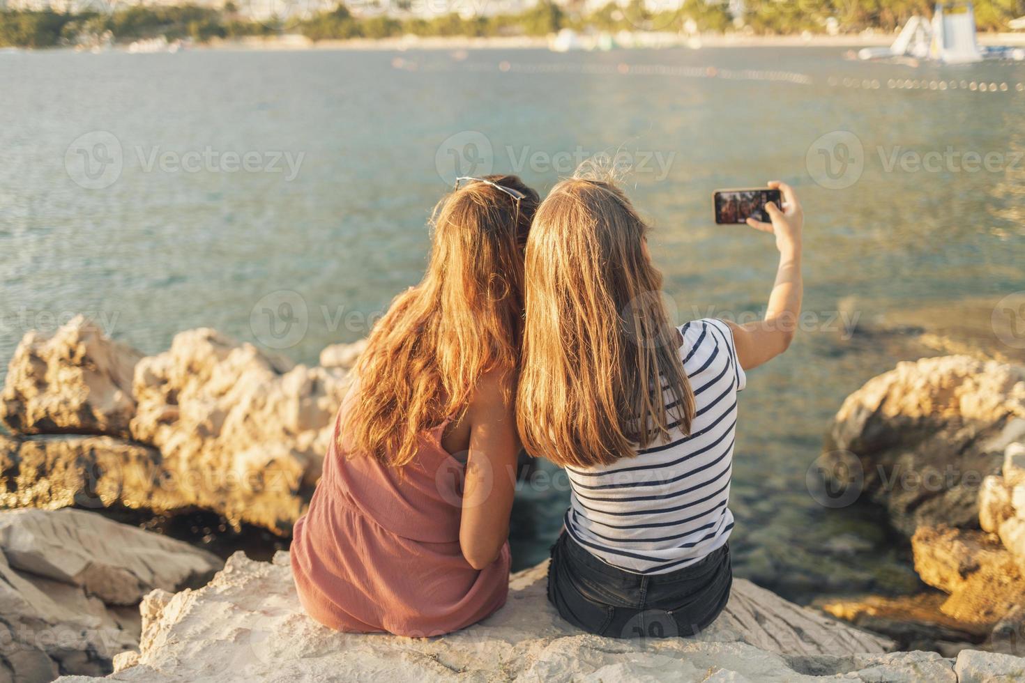 Due femmina amici avendo divertimento mentre fabbricazione un' video chiamata a estate vacanza foto