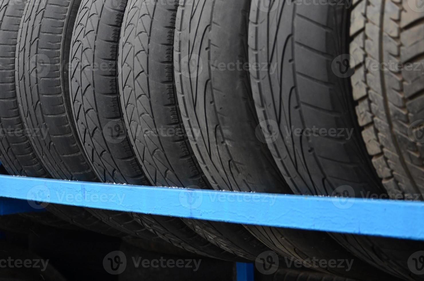 cremagliera con varietà di auto pneumatici nel automobile negozio. molti nero pneumatici. pneumatico pila sfondo. selettivo messa a fuoco foto