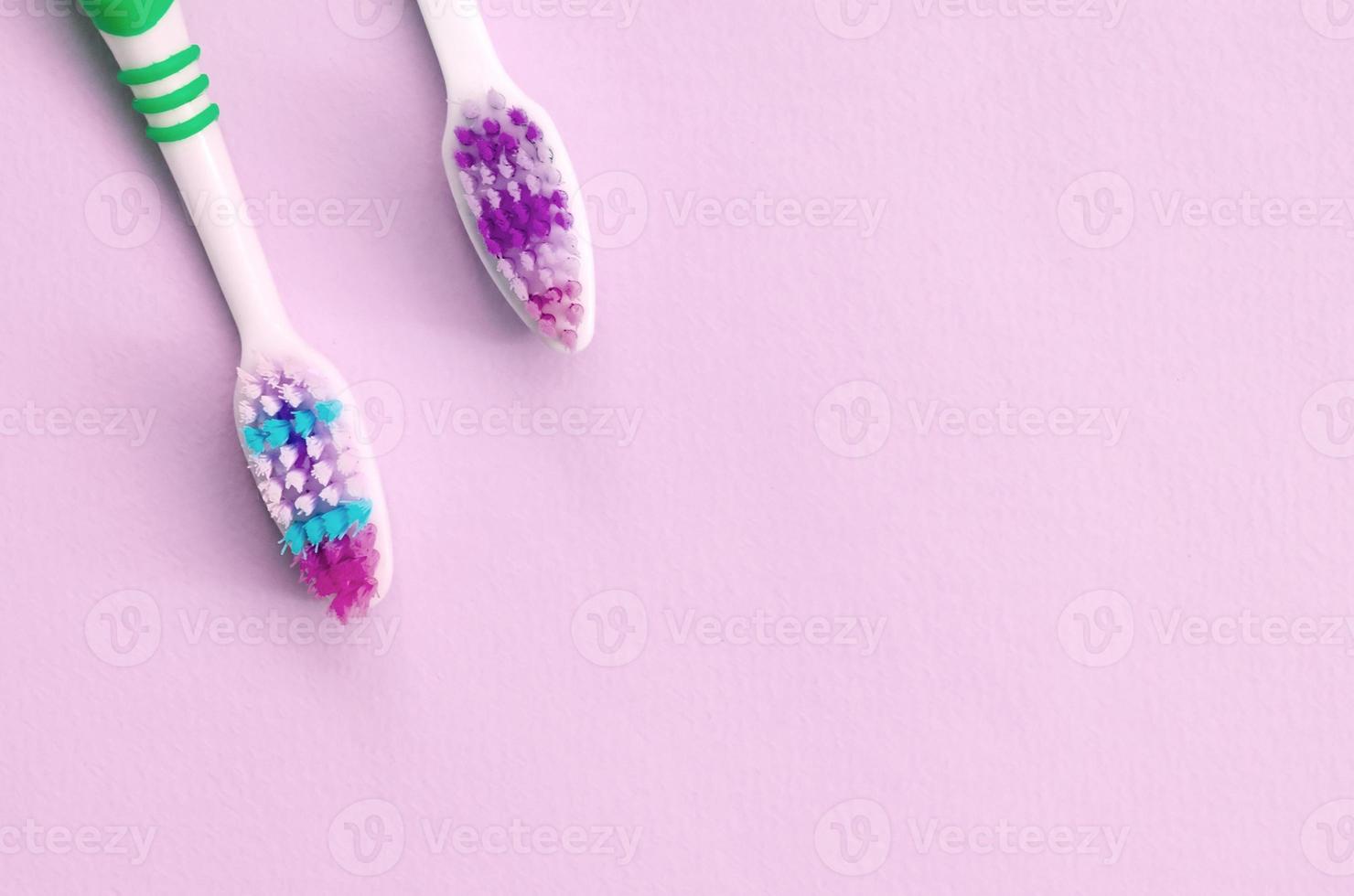 Due spazzolini da denti menzogna su un' pastello rosa sfondo foto