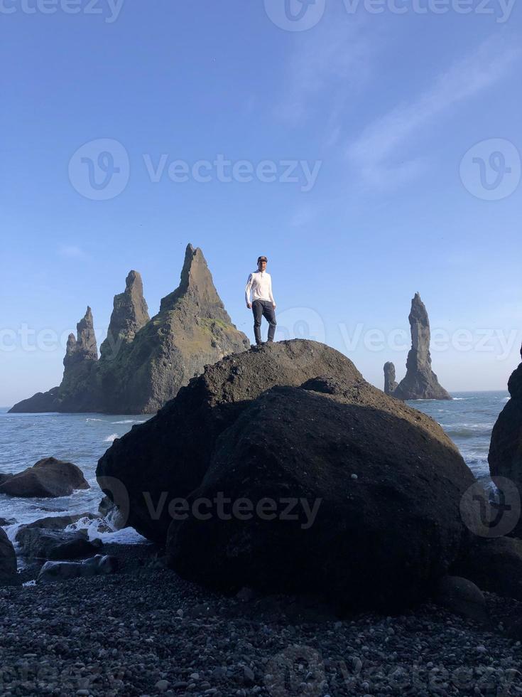 uomo in piedi su un' roccia a reynisfjara nero spiaggia, Islanda, con vento nel il suo capelli foto