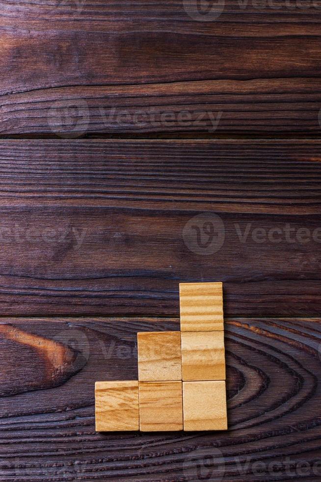un' di legno blocchi cubo al di sopra di nero di legno strutturato sfondo con copia spazio per Inserisci parola testo titolo. concetto o concettuale legna bloccare scala o tre passi. cubo foto