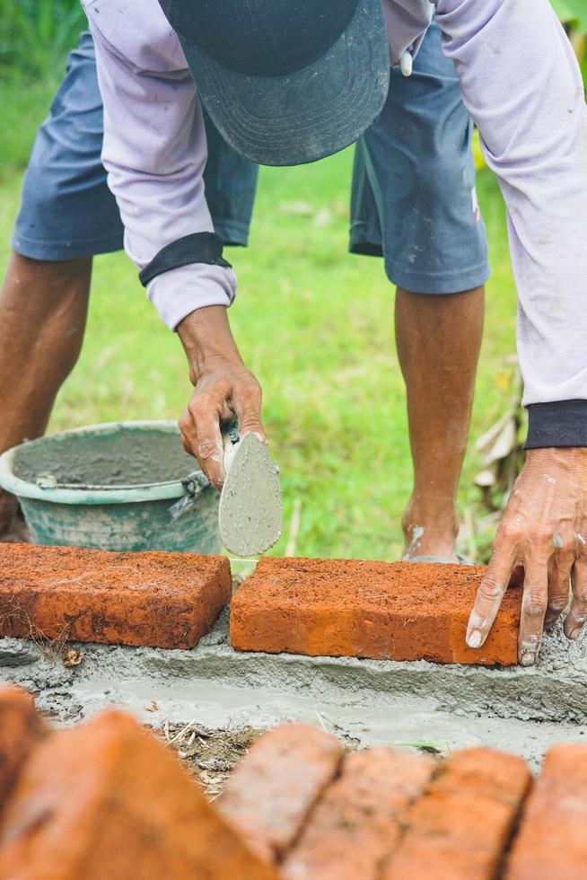 costruzione lavoratori installare mattoni e cemento a partire dal righe di mattoni su esterno muri foto