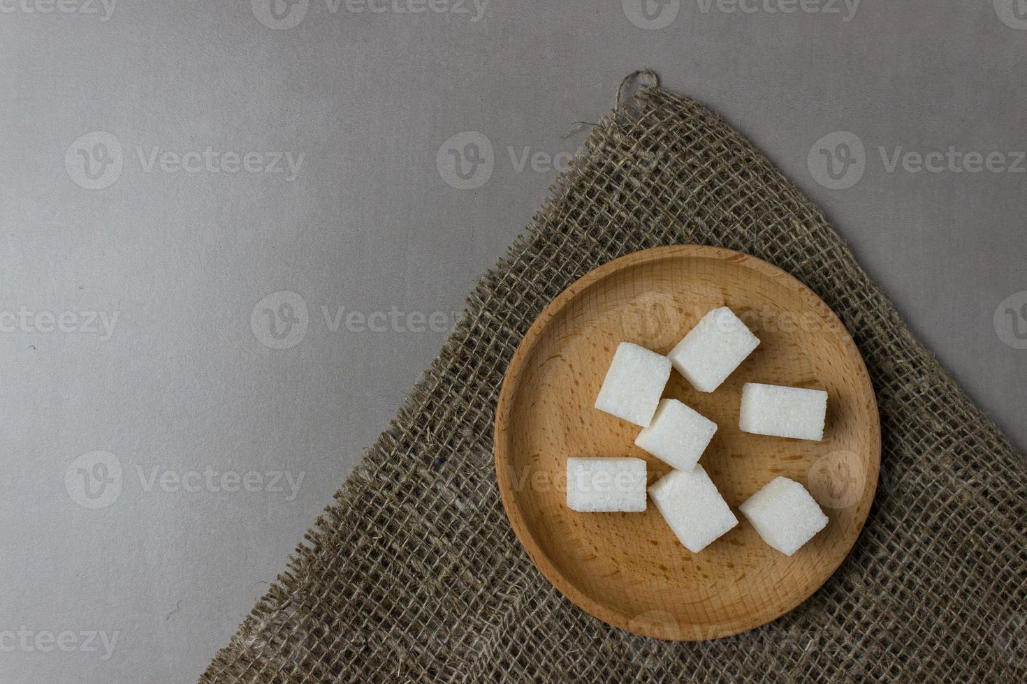 zucchero cubi nel un' di legno piatto su tela di sacco su il cucina tavolo. superiore Visualizza. con copia spazio foto