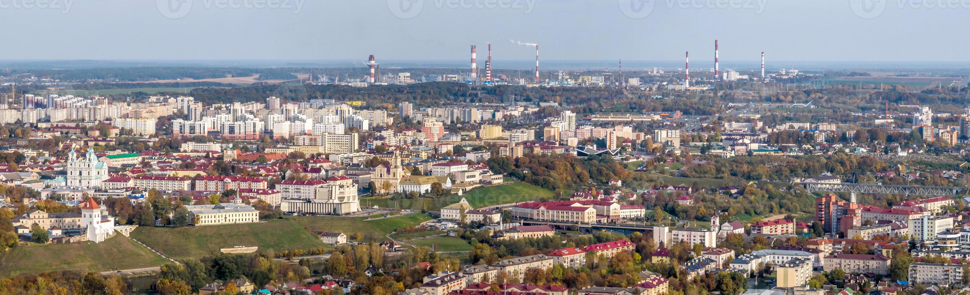 ariel panoramico Visualizza di vecchio città e moderno grattacieli con un' enorme fabbrica con fumo camini nel il sfondo foto