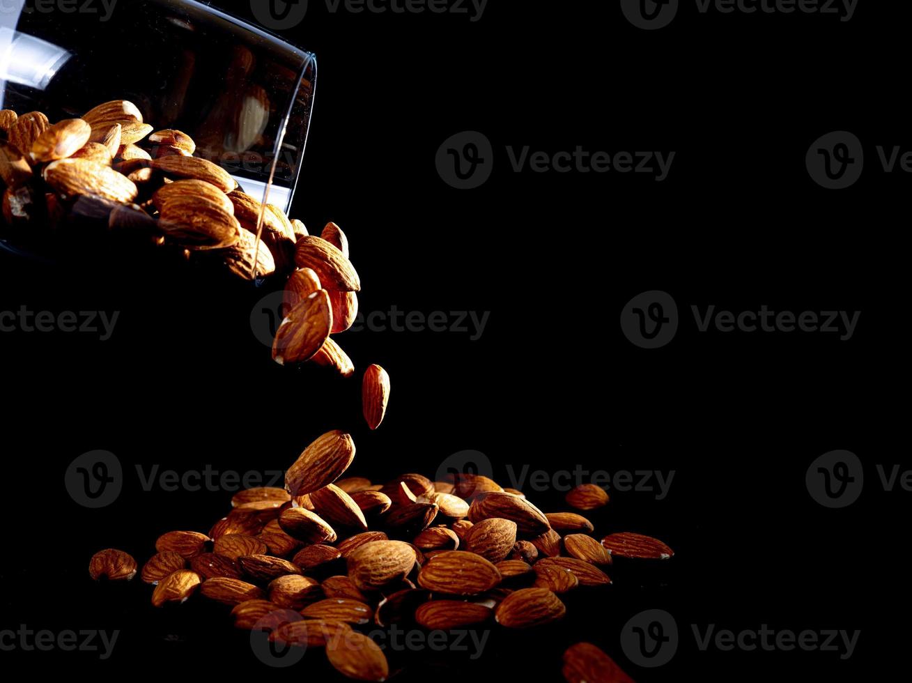 pelato mandorla nel vaso bicchiere di vino secchio su un' nero isolato sfondo. riga di ciotole con mandorla noccioline, davanti Visualizza. foto