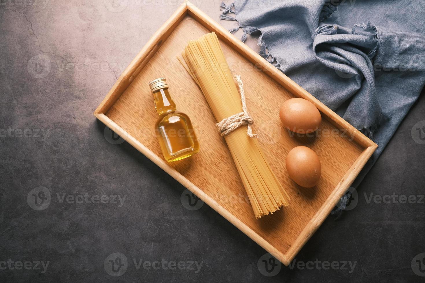 spaghetti lunghi gialli uovo e olio sul tavolo foto