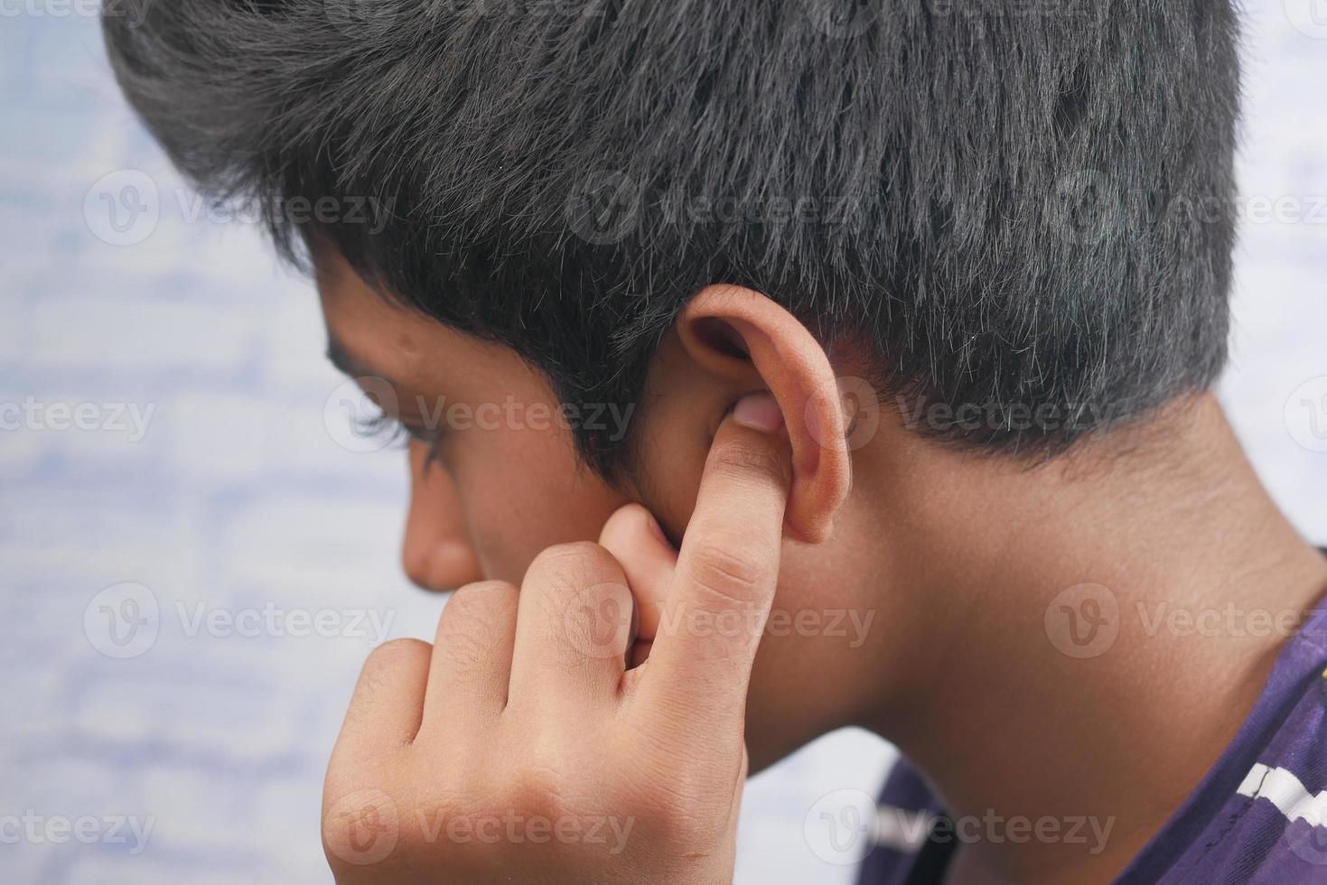 ragazzo adolescente che ha dolore all'orecchio che tocca il suo orecchio doloroso, foto