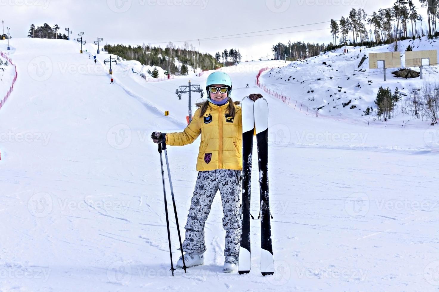 contento sorridente giovane donna nel giallo giacca e sciare casco sciare su un' montagna pendenza, inverno gli sport, alpino sciare all'aperto attività, salutare stile di vita foto