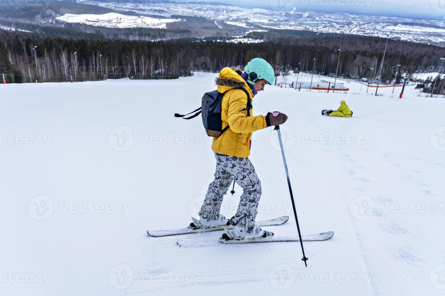 giovane donna nel giallo giacca e sciare casco sciare giù su montagna pendenza, inverno gli sport, alpino sciare all'aperto attività, salutare stile di vita foto