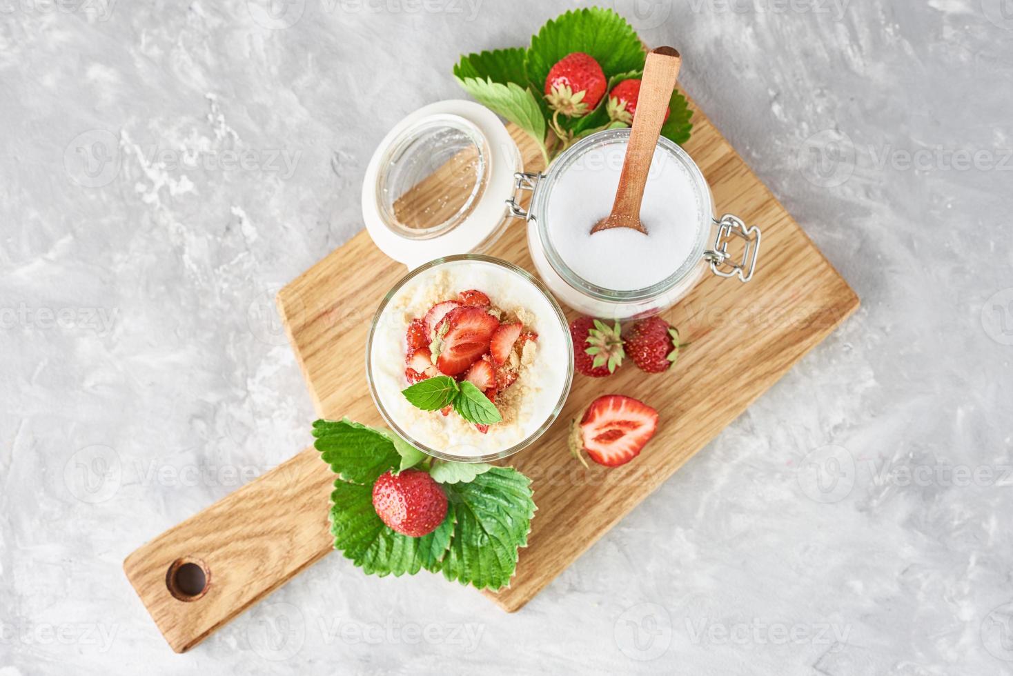 muesli o Yogurt con fragola nel bicchiere, fresco frutti di bosco e vaso con zucchero foto