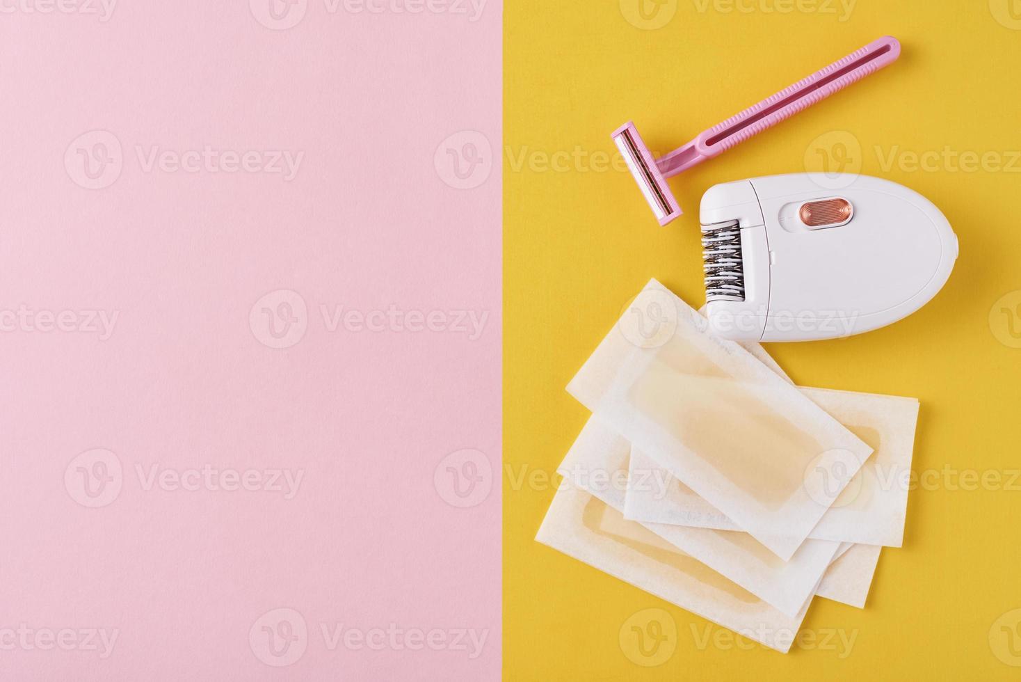 epilatore, rasoio e cera strisce su giallo e rosa foto