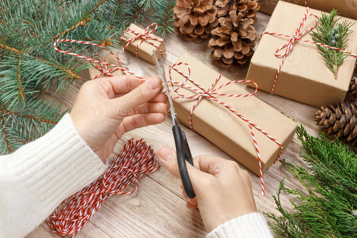 Natale regalo involucro sfondo. femmina mani confezione Natale presente avvolto nel kraft carta superiore Visualizza. inverno vacanze concetto piatto posare donna Tenere Natale regalo scatola foto