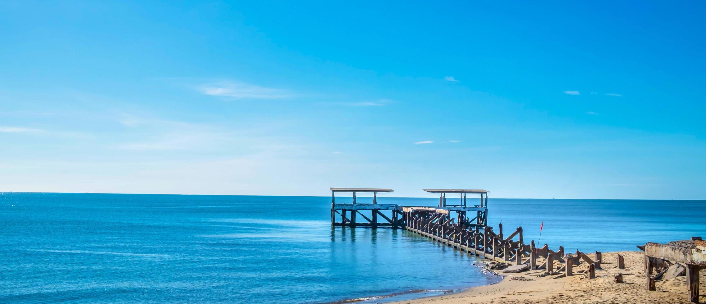 il paesaggio di tropicale sabbioso spiagge con mare e blu estate cieli è bellissimo con un vecchio rotto ponte principale per il mare. foto