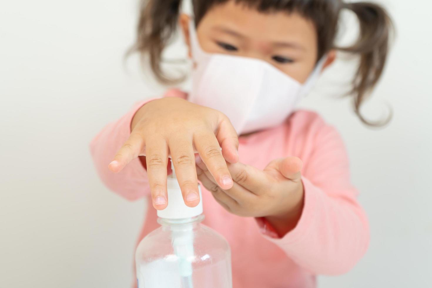 bambina utilizzando disinfettante per le mani foto