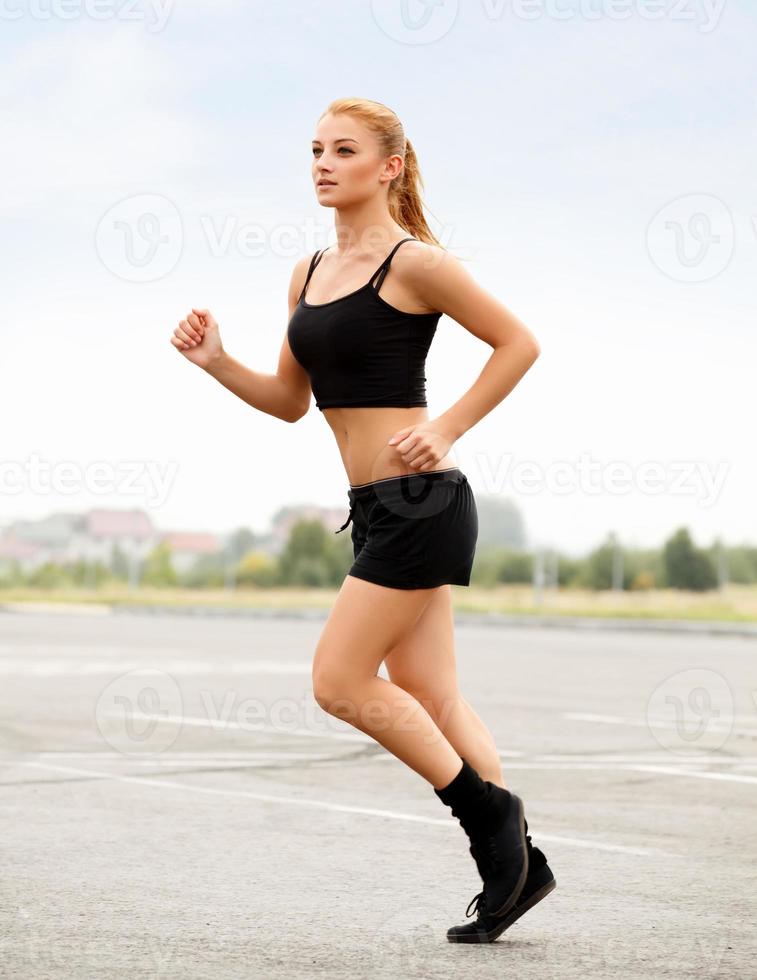 corridore atletico formazione in un parco. ragazza fitness in esecuzione all'aperto foto