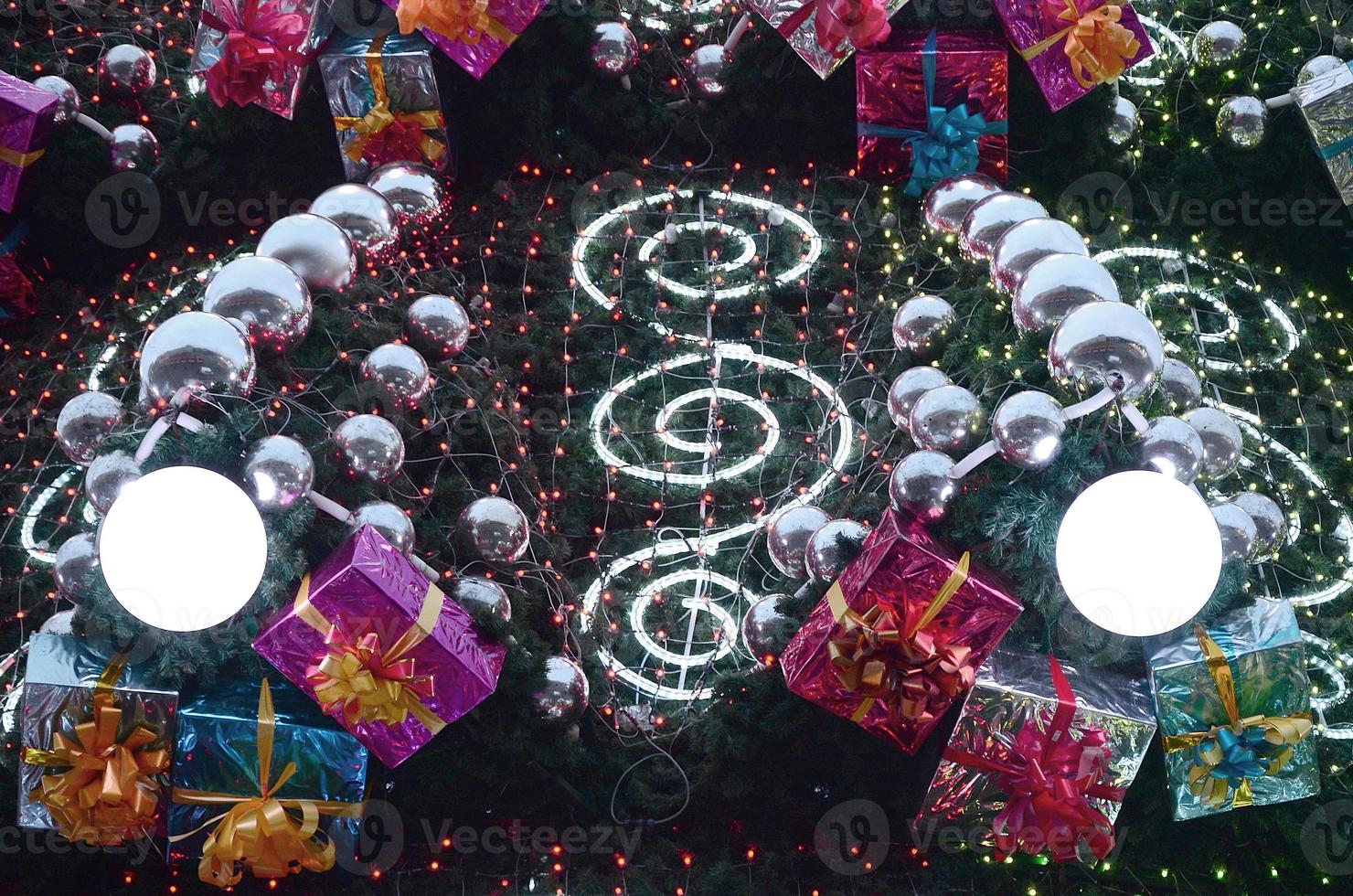 un' frammento di un' enorme Natale albero con molti ornamenti, regalo scatole e luminoso lampade. foto di un' decorato Natale albero avvicinamento