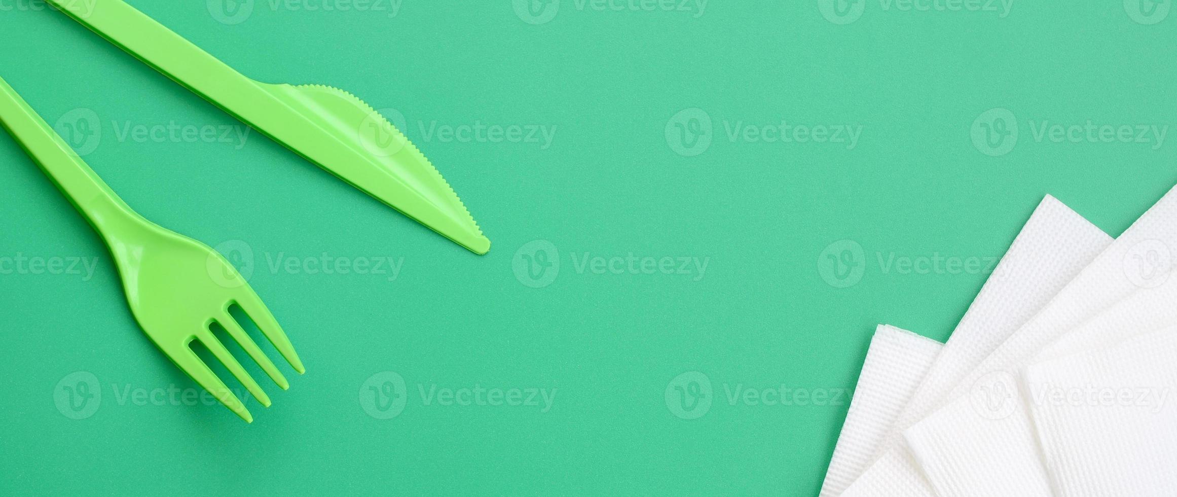 monouso plastica posate verde. plastica forchetta e coltello menzogna su un' verde sfondo superficie Il prossimo per tovaglioli foto