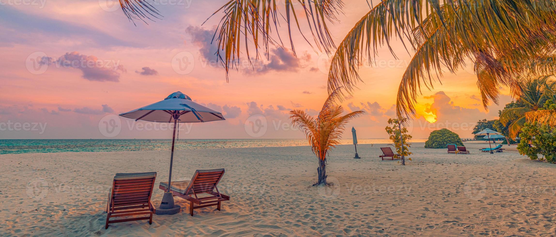 tranquillo romantico spiaggia scena. coppia sedie ombrello, esotico tropicale spiaggia paesaggio per sfondo sfondo. panoramico estate vacanza vacanza striscione. ricorrere costa, palma le foglie tramonto mare cielo sabbia foto