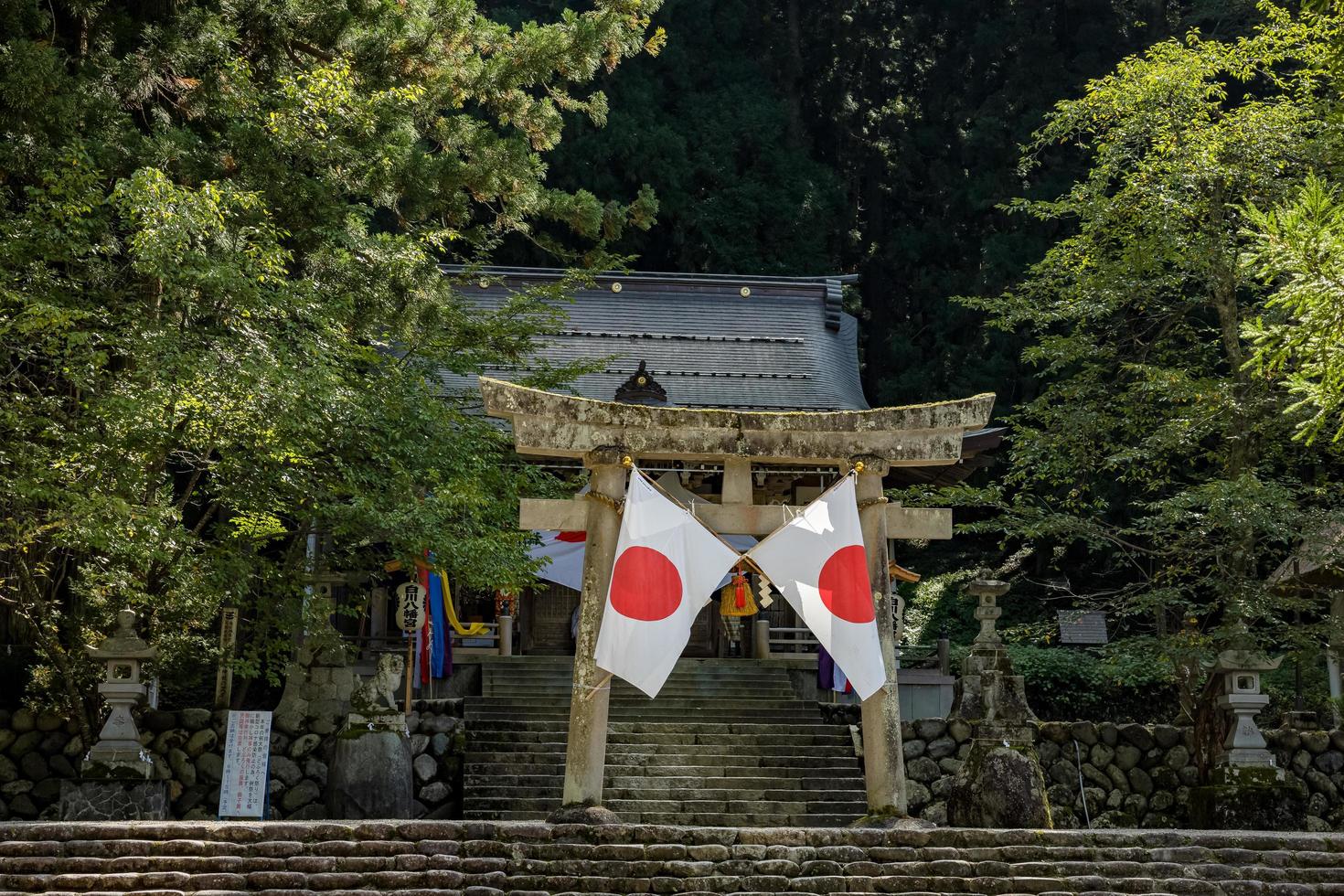 Shirakawago, gifu, Giappone - ottobre 2022 - shirakawa hachiman santuario cancello la zona a shirakawago villaggio con pino alberi e giapponese bandiera. foto