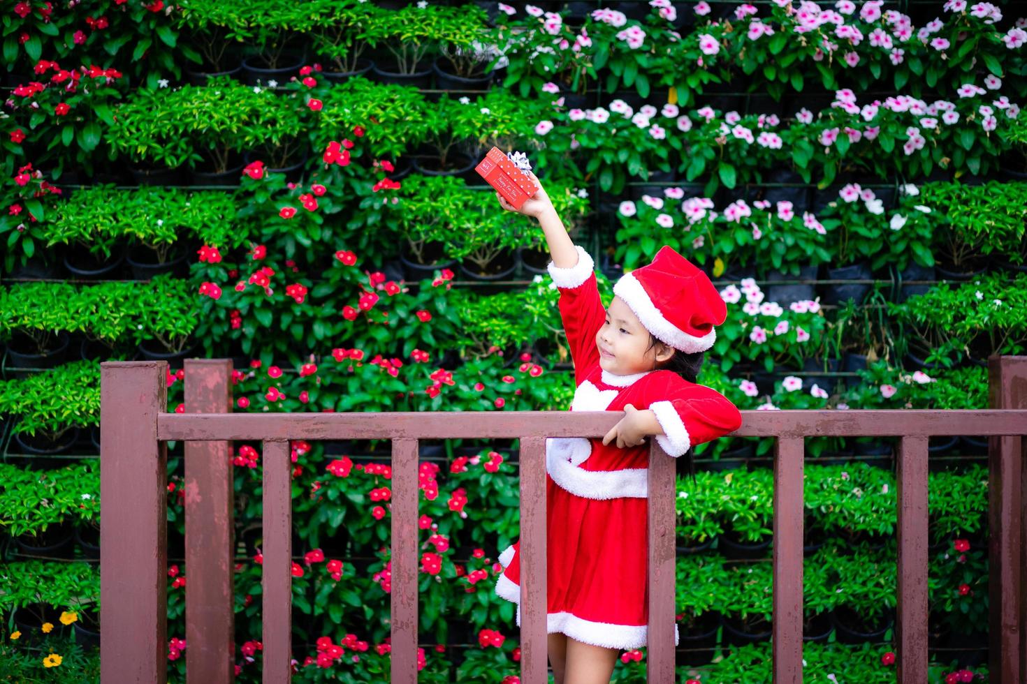 piccola ragazza asiatica in costume rosso di Babbo Natale con la presente scatola nel parco foto