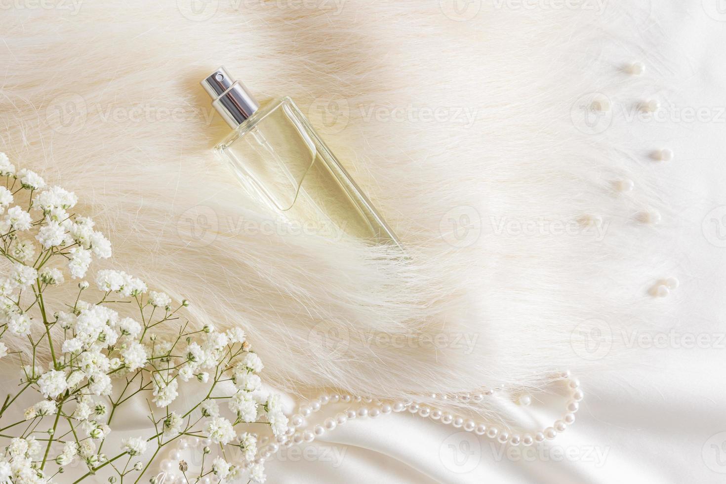 un elegante bottiglia di Da donna profumo è sepolto nel un' mucchio di beige pelliccia. perla perline e gypsophila fiori. costoso fragranza. superiore Visualizza. foto