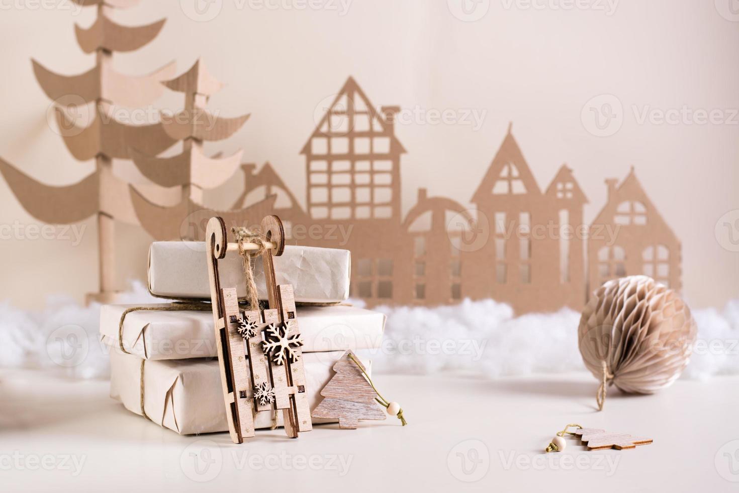 Fai da te Natale casa arredamento - di legno slitta vicino mucchio di i regali, cartone albero e Casa. fatto a mano foto