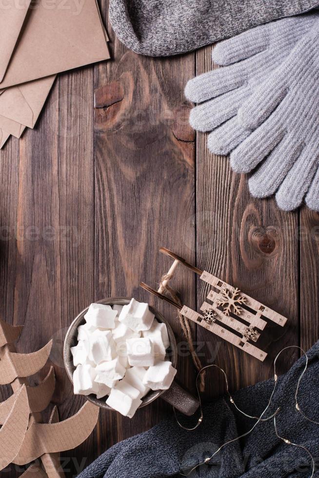 inverno ancora vita. bevanda con marshmallow, slitta, di lana calzini e guanti su un' di legno sfondo. foto