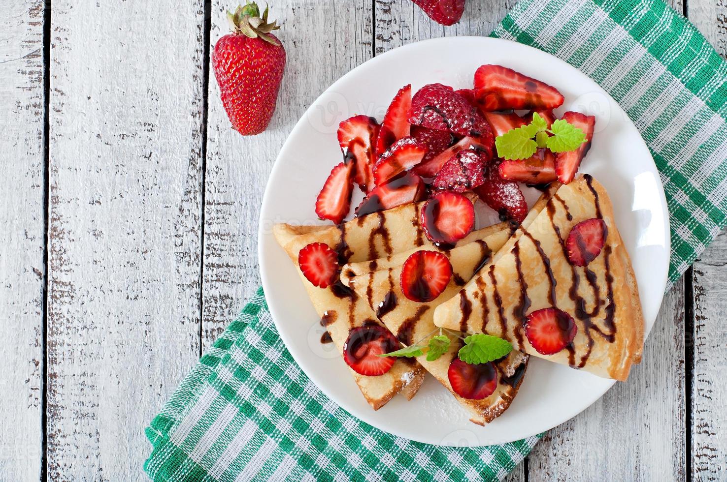 Pancakes con fragole e cioccolato decorato con menta foglia foto