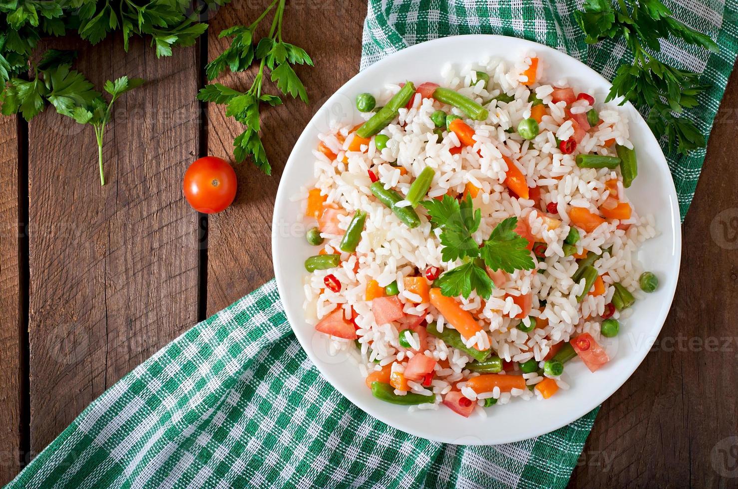 appetitoso salutare riso con verdure nel bianca piatto su un' di legno sfondo. foto