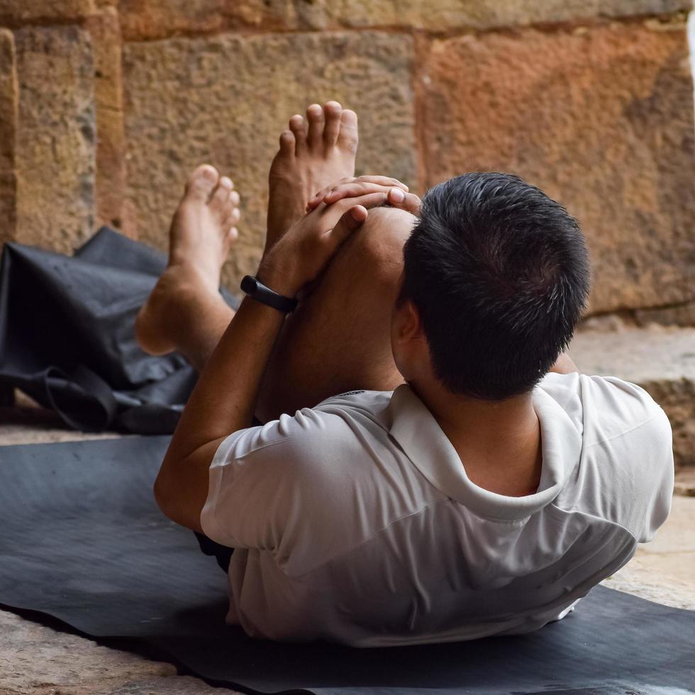 delhi, India, giugno 18 2022 - ispirato indiano giovane uomo fare yoga asana nel lodhi giardino parco, nuovo delhi, India. giovane cittadino esercizio al di fuori e in piedi nel yoga lato angolo posa foto