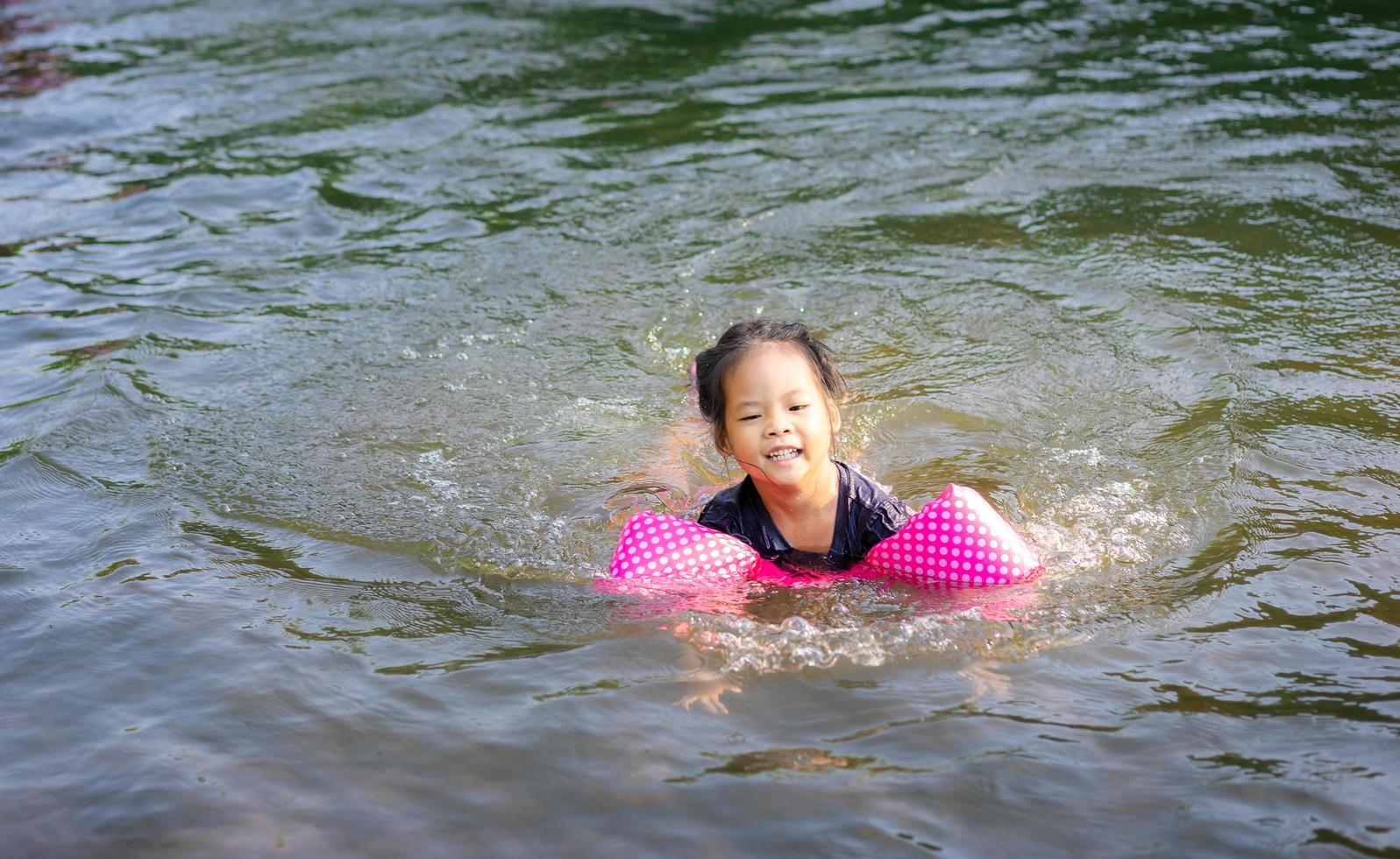 piccola ragazza asiatica che nuota nel fiume foto