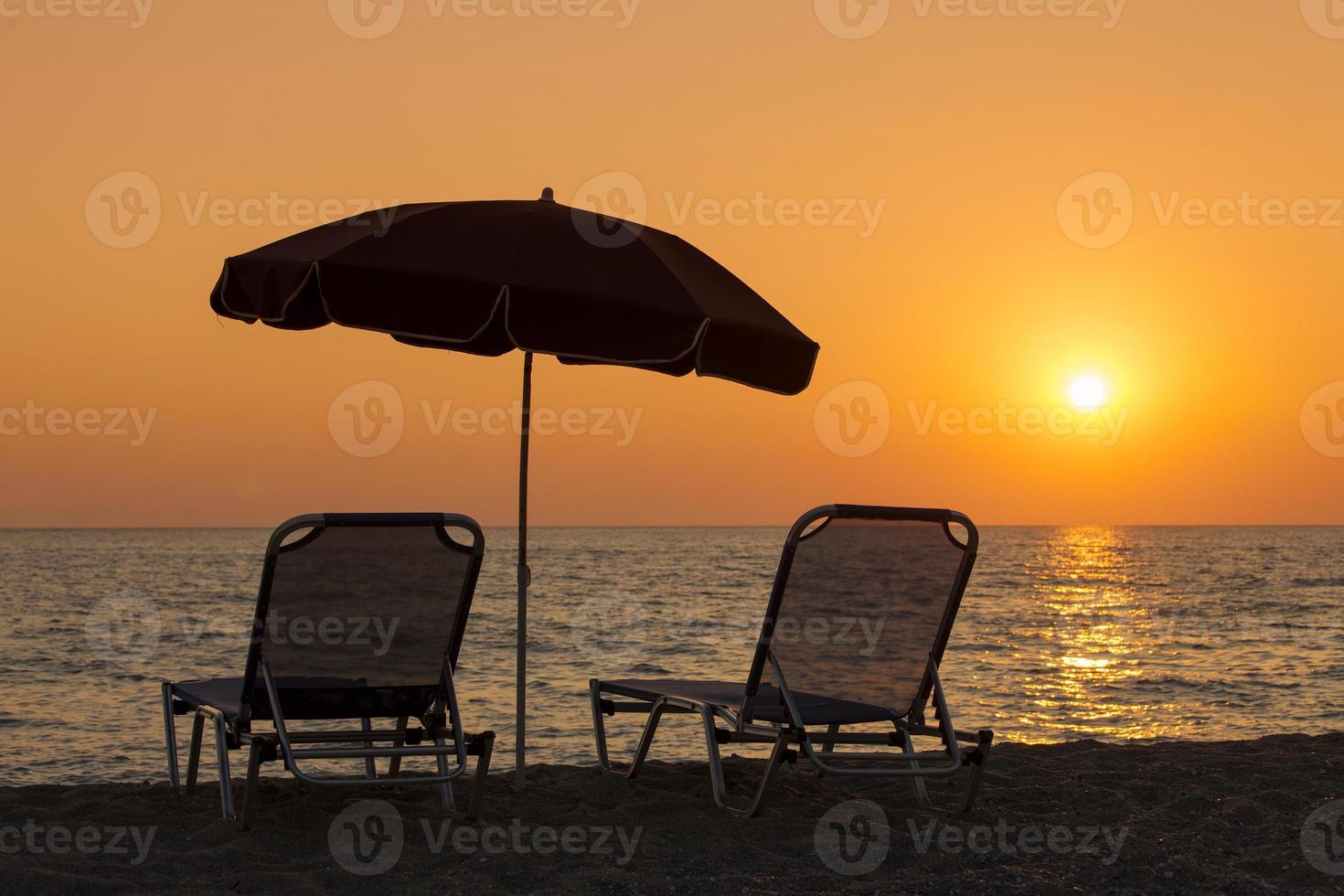 bellissima spiaggia con sdraio e ombrellone al tramonto foto