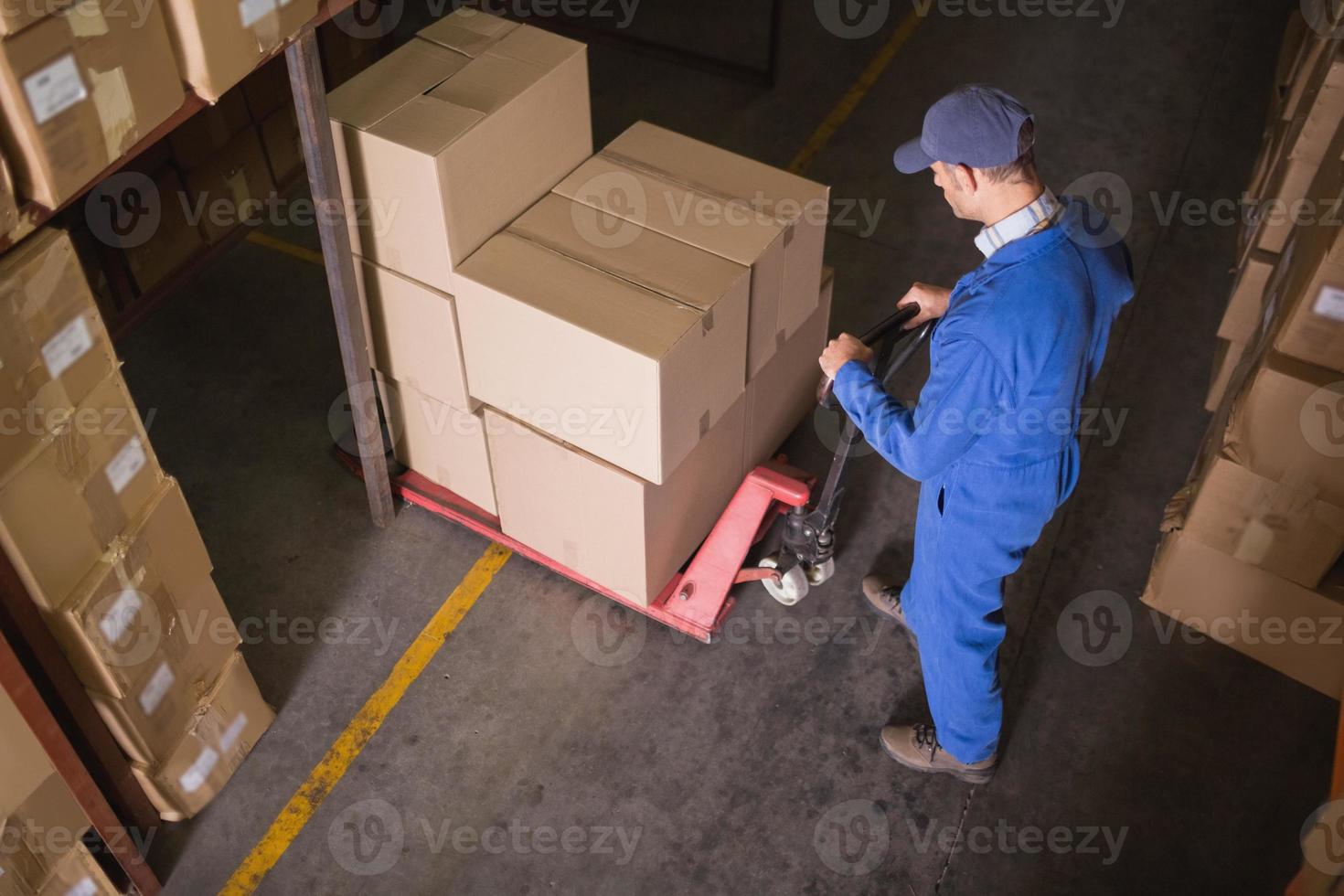 lavoratore spingendo il carrello con scatole in magazzino foto