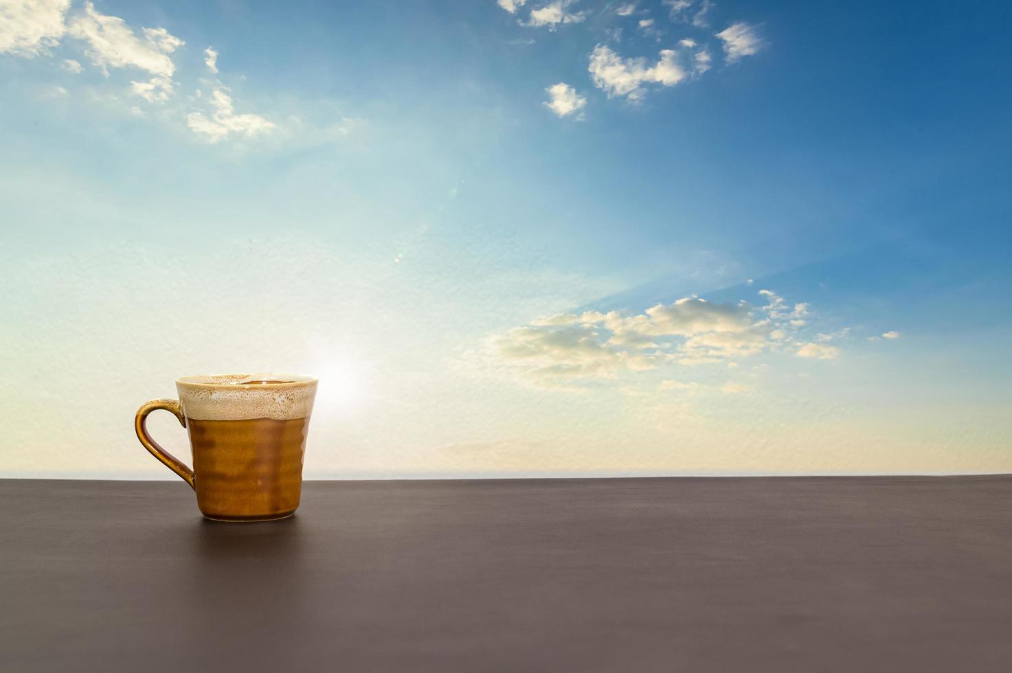 tazza di caffè sul tavolo con vista del cielo e delle nuvole foto