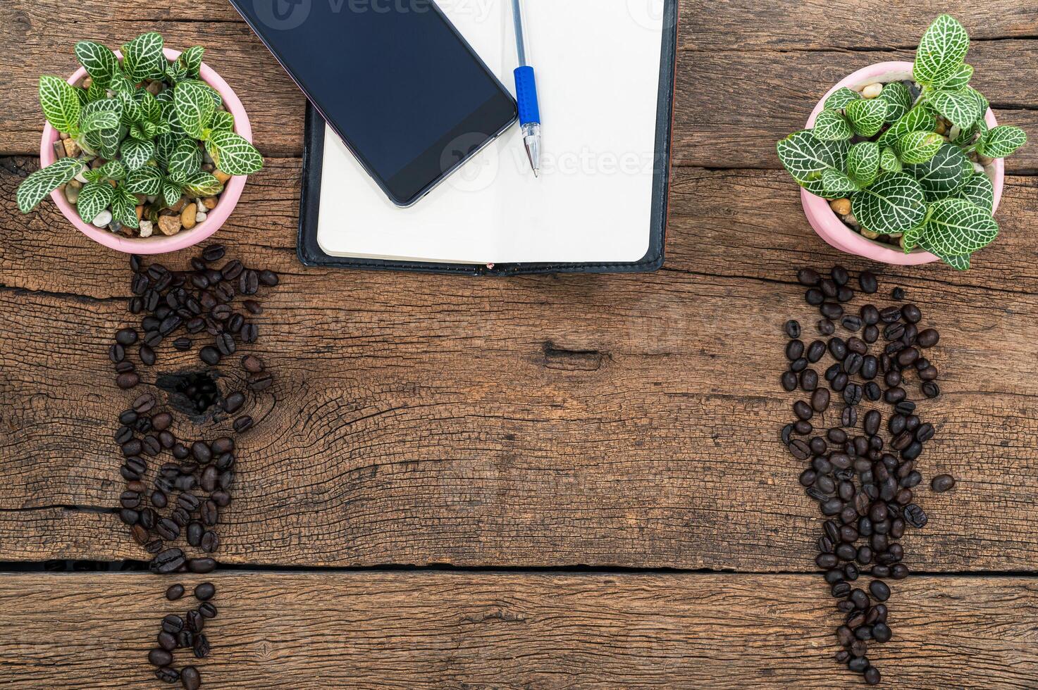 taccuino, chicchi di caffè e vasi di fiori sulla scrivania foto