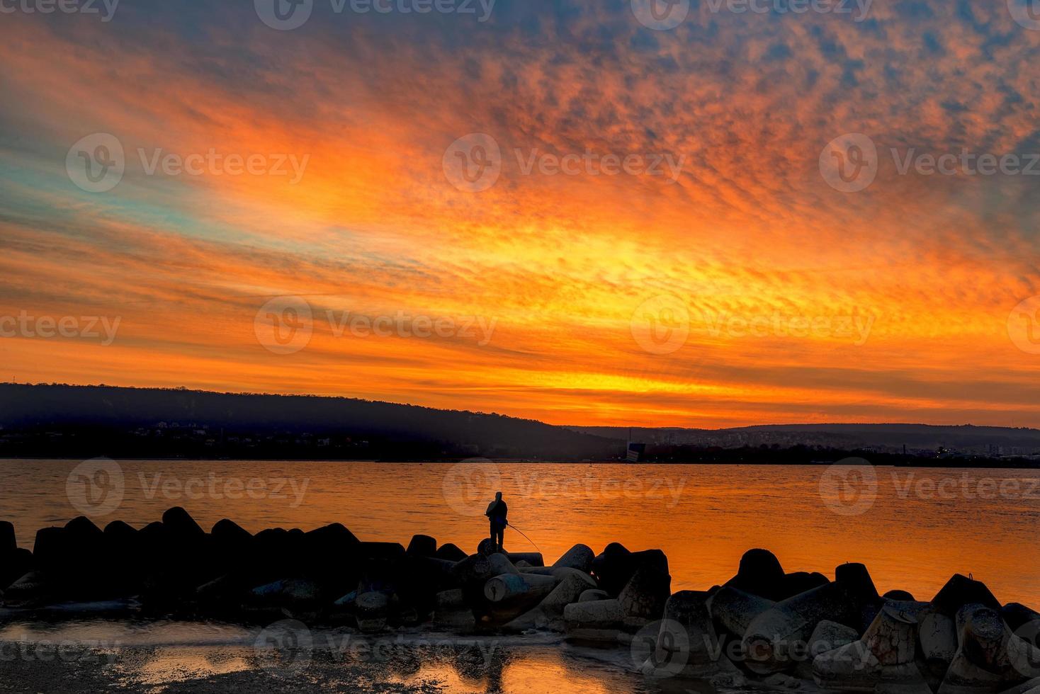 pesca e pescatore nel mare a sorprendente tramonto foto