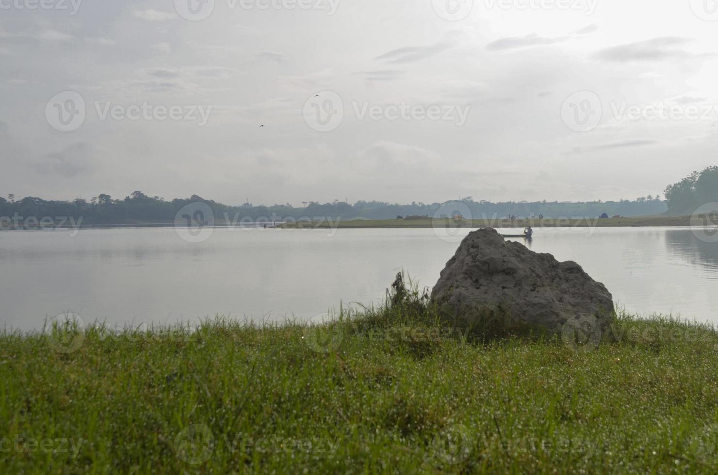 davanti Visualizza di serbatoio karangkate malang Indonesia fra montagne con nebbioso cielo dietro a e un' pietra e prati nel il primo piano foto
