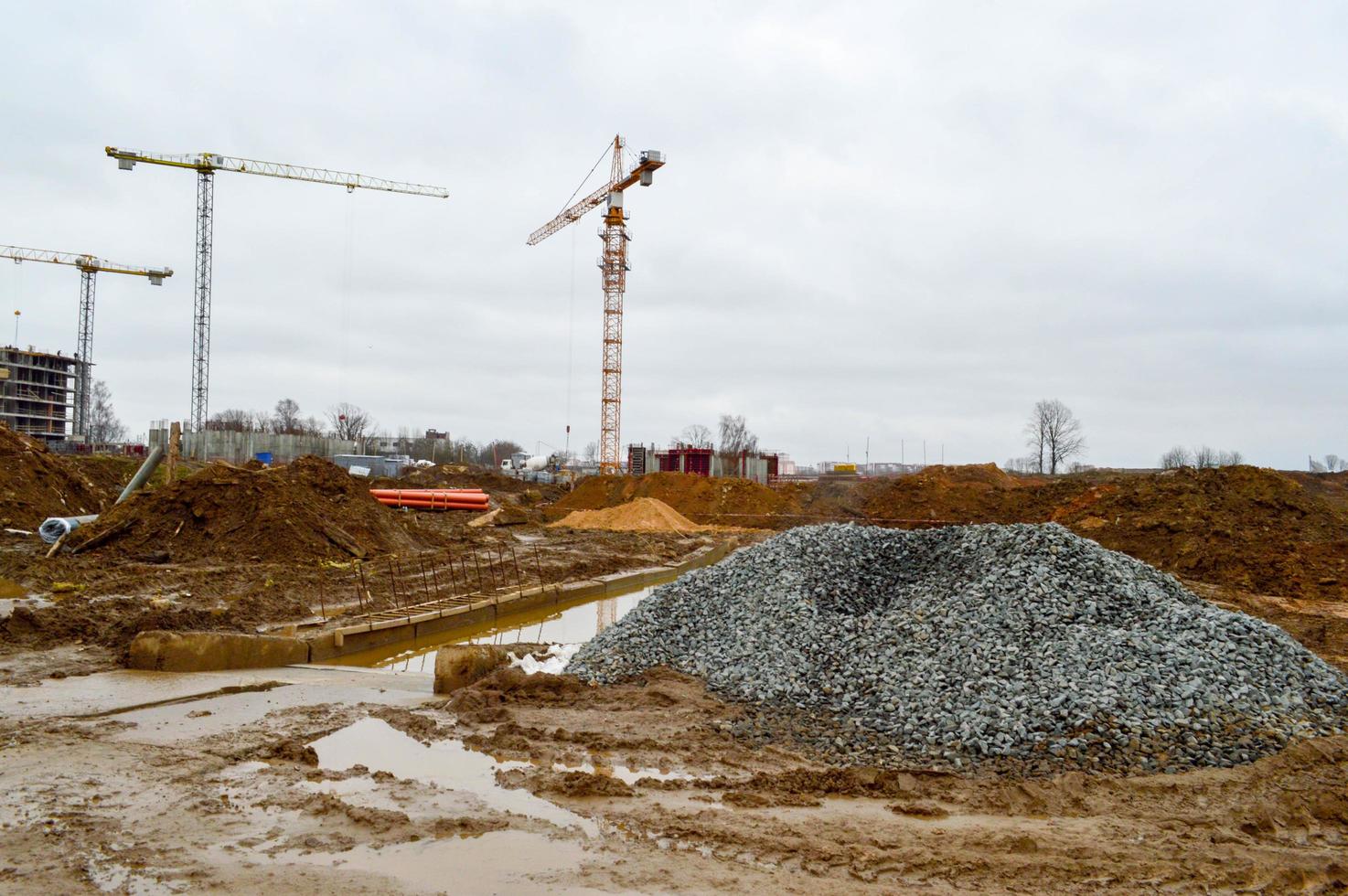 un' grande moderno costruzione luogo nel il costruzione di edifici e case con elettrodomestici e molti grande alto Torre e stazionario industriale potente gru e edificio materiale foto