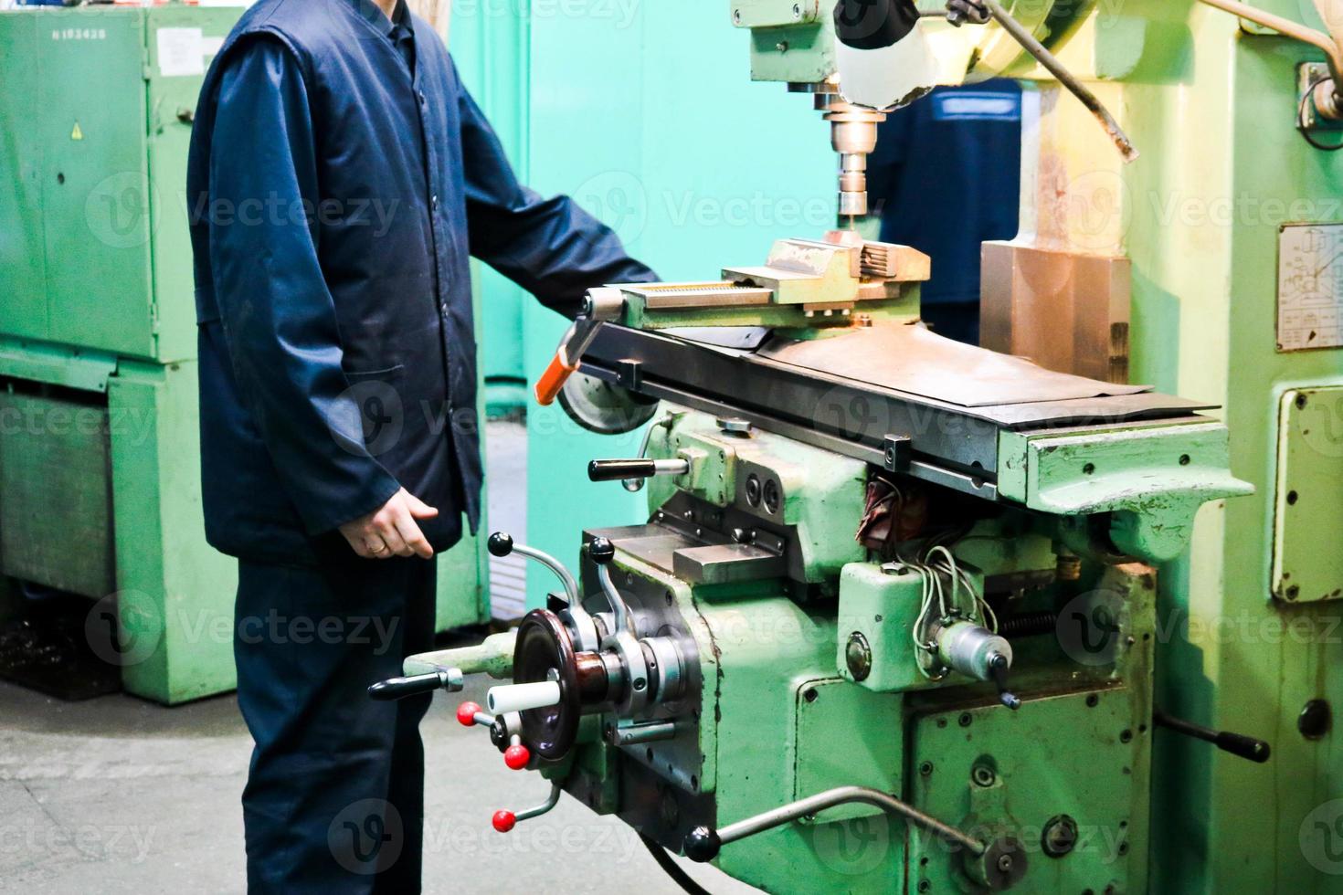 un' maschio lavoratore lavori su un' più grandi metallo ferro fabbro ferraio tornio, attrezzatura per riparazioni, metallo opera nel un' laboratorio a un' metallurgico pianta nel un' riparazione produzione foto