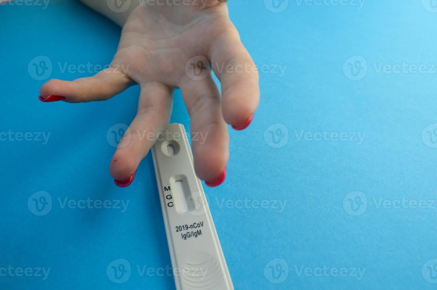 sangue test per il diagnosi di coronavirus. test striscia e dito foratura su un' blu Opaco sfondo. ragazze mano nel anticipazione di un' foratura di il squillare dito foto