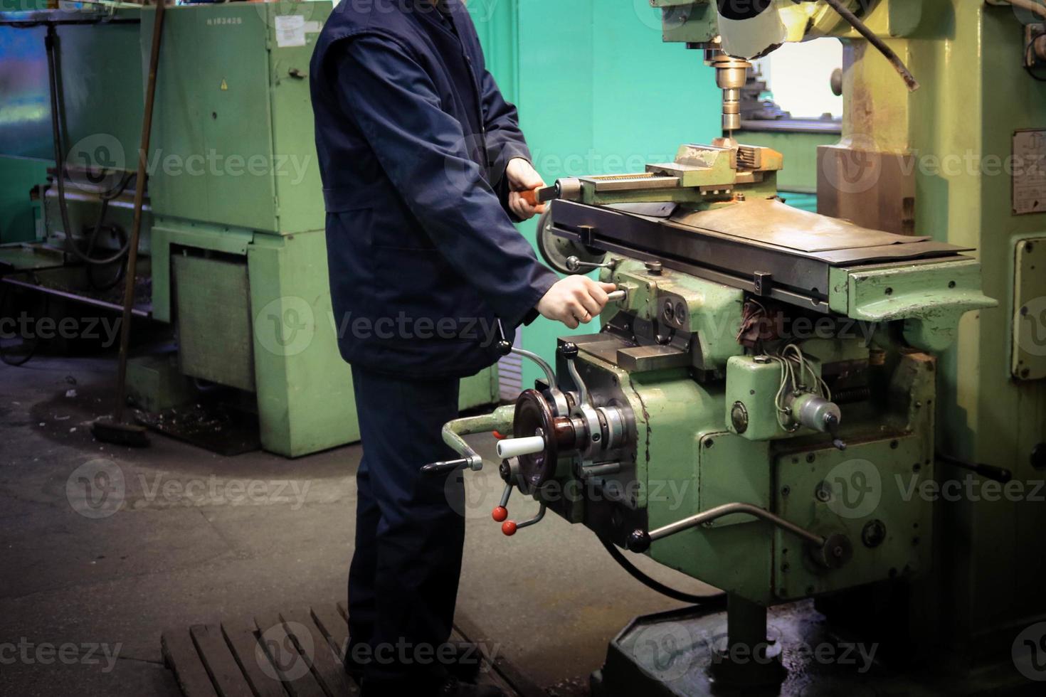 un' maschio lavoratore lavori su un' più grandi metallo ferro fabbro ferraio tornio, attrezzatura per riparazioni, metallo opera nel un' laboratorio a un' metallurgico pianta nel un' riparazione produzione foto