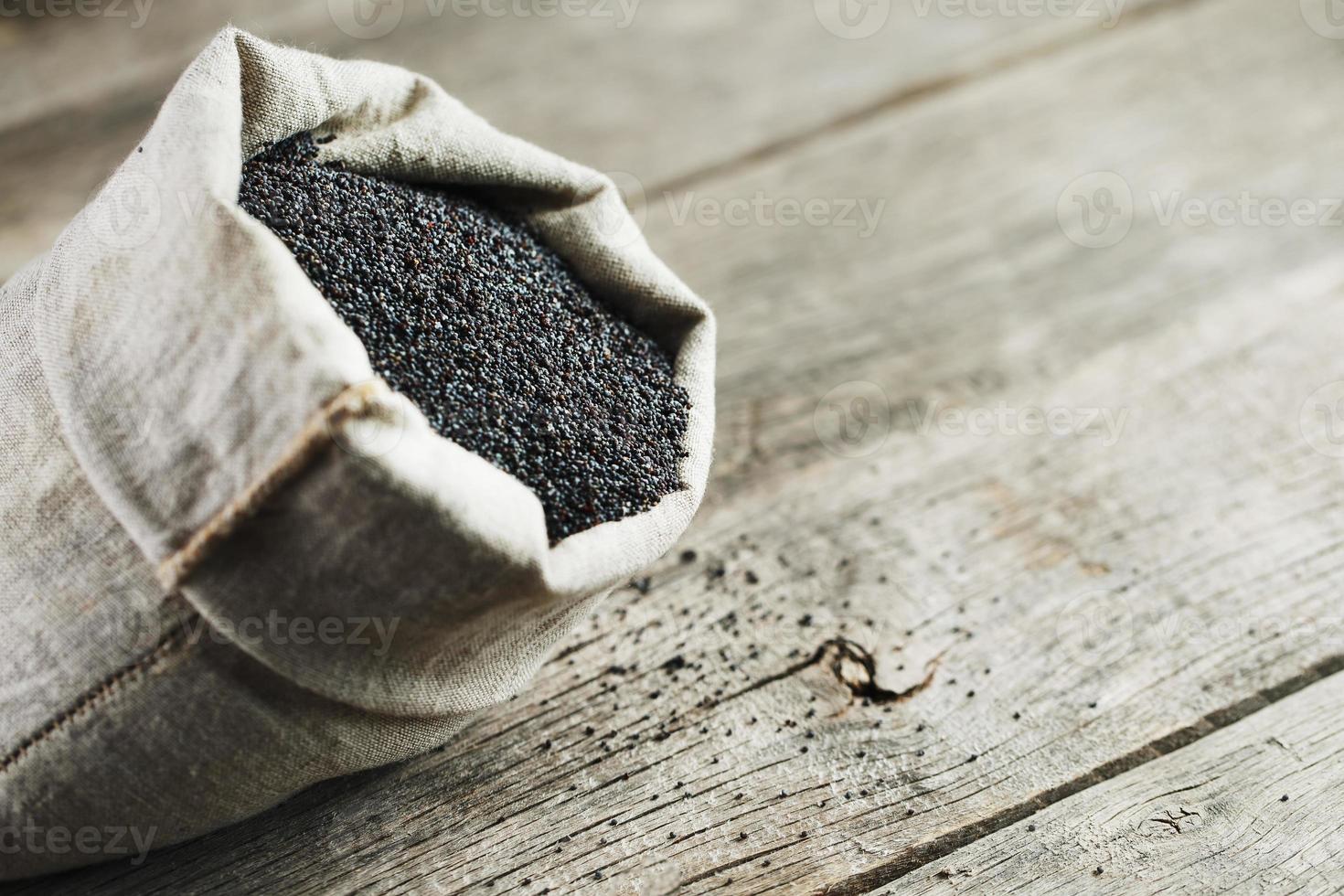 papavero semi nel un' tela ruvida Borsa su un' Vintage ▾ di legno grigio sfondo. il gustoso e utile semi ricco con proteina e oli. foto