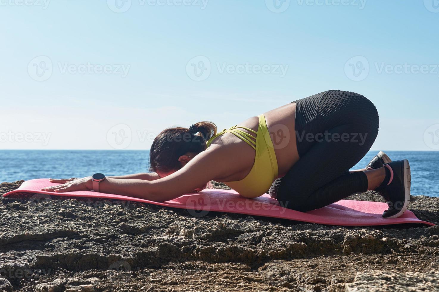 latino donna, di mezza età, indossare abbigliamento sportivo, addestramento, fare fisico esercizi, tavola, sit-up, quello dello scalatore fare un passo, ardente calorie, conservazione in forma, all'aperto di il mare, indossare cuffia, inteligente orologio foto