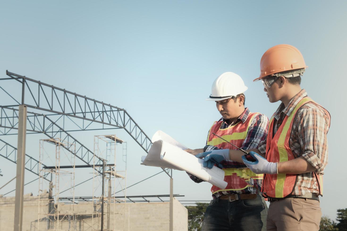 strutturale ingegnere e lavoratore Lavorando con progetti discutere a il all'aperto costruzione luogo. foto